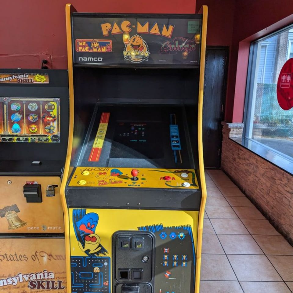 A classic yellow Pac-Man arcade game stands next to a skill game machine in Stoli's Steaks.